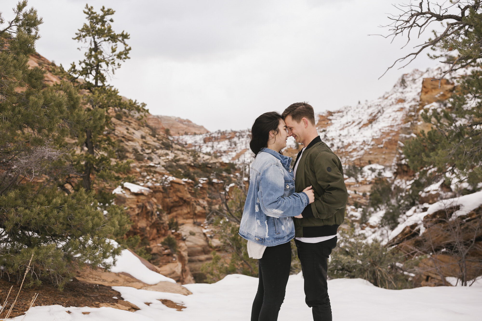 Engaged couple snuggle close in the snow at Zion National Park