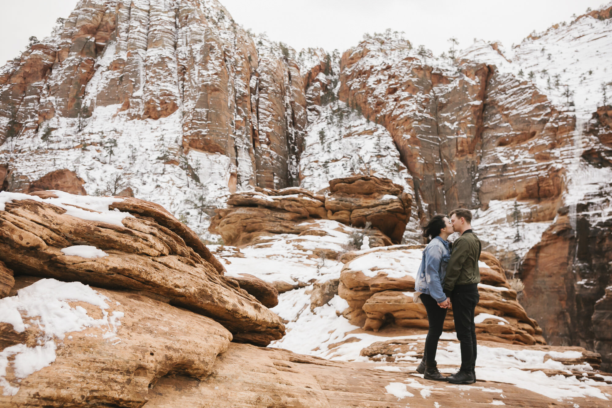 Adventurous couple kiss at a canyon overlook in Zion in Utah