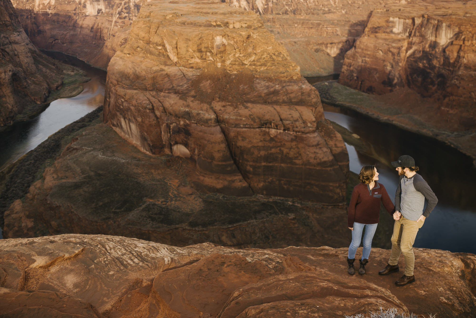 Adventurous couple stand on the edge of Horseshoe Bend at sunrise
