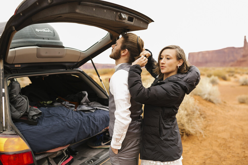 Wedding couple get ready for their elopement at their car in Monument Valley