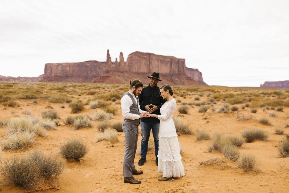 Couple exchange rings in the desert at Monument Valley wedding