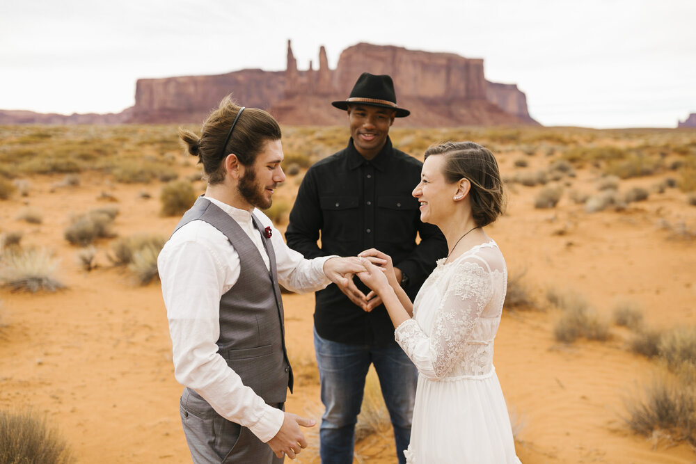 Couple exchange rings in the desert at Monument Valley wedding