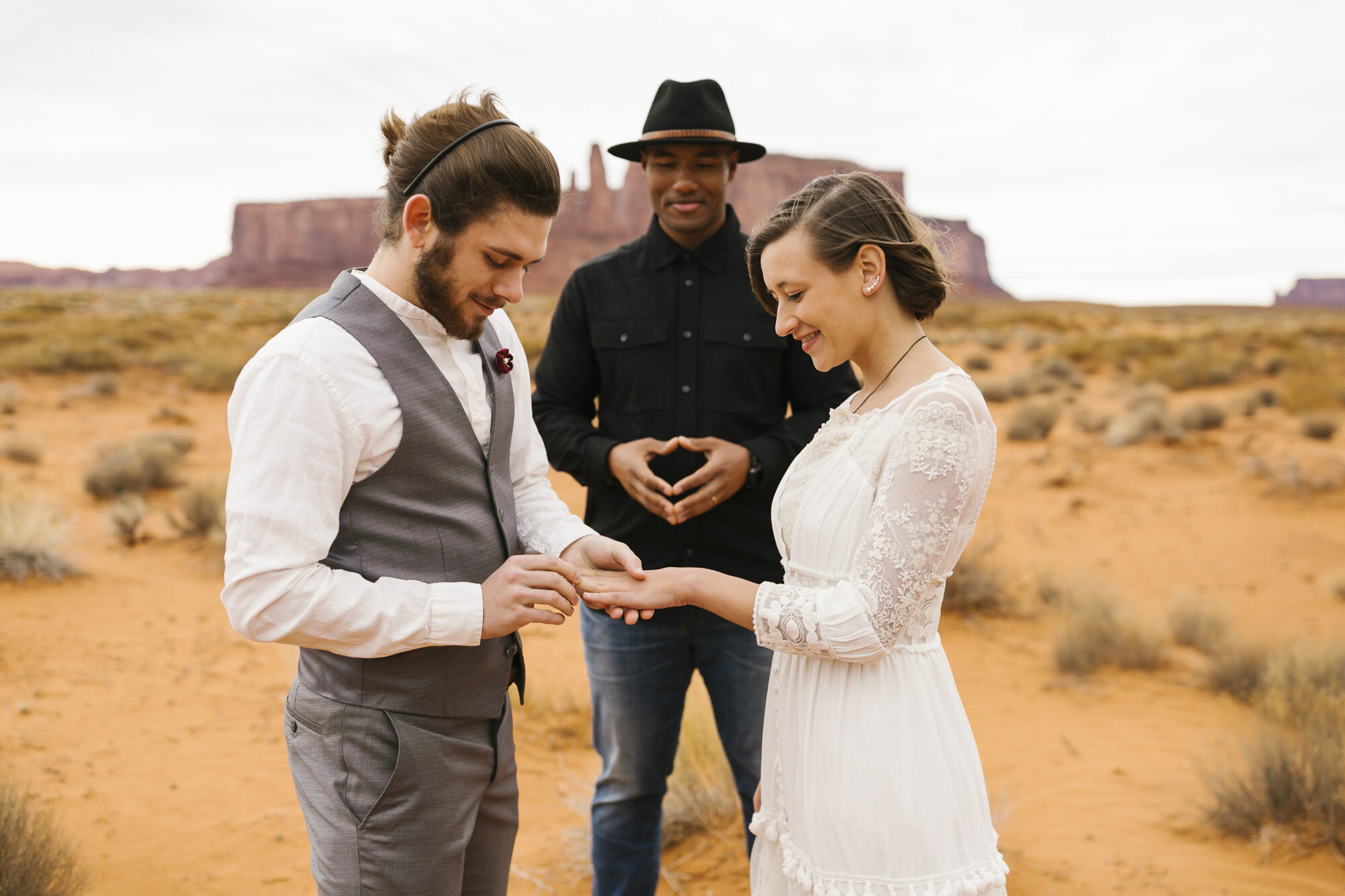 Bride and groom exchange rings during their ceremony at their Monument Valley wedding