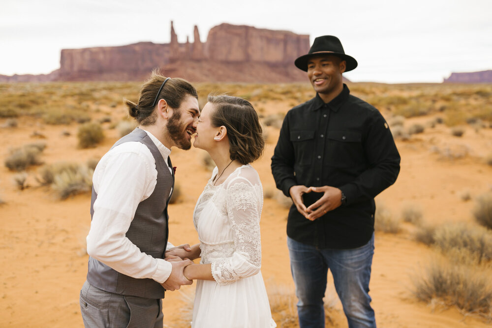 Couple smile and kiss after their wedding ceremony in Monument Valley wedding
