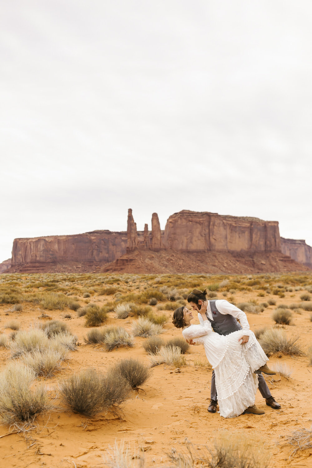 Groom dips his bride to celebrate getting married in the Utah desert at their Monument Valley wedding