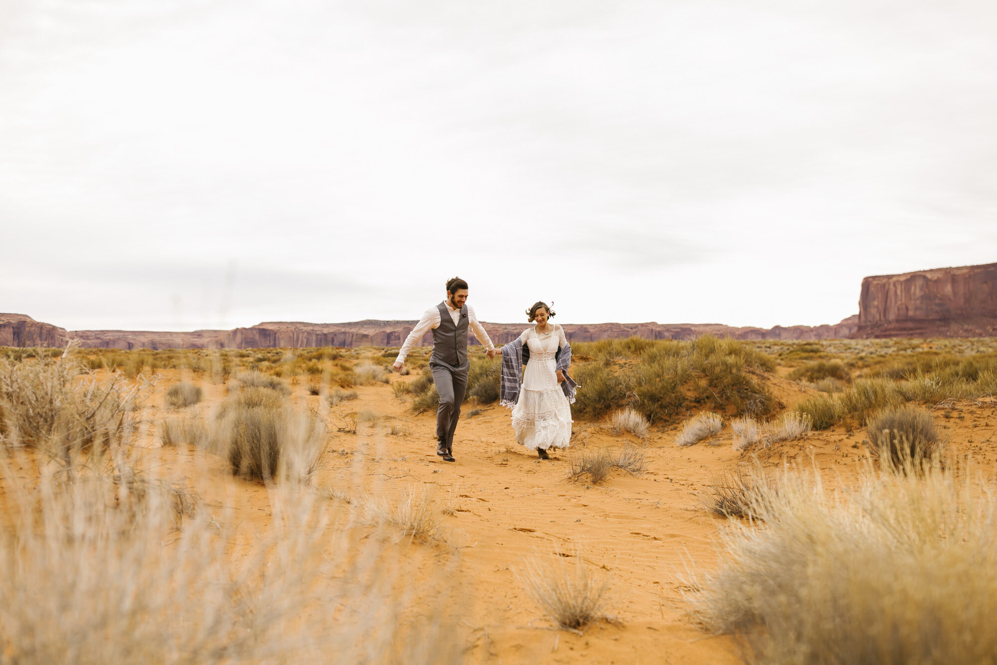 Couple runs through the desert together at their Monument Valley wedding