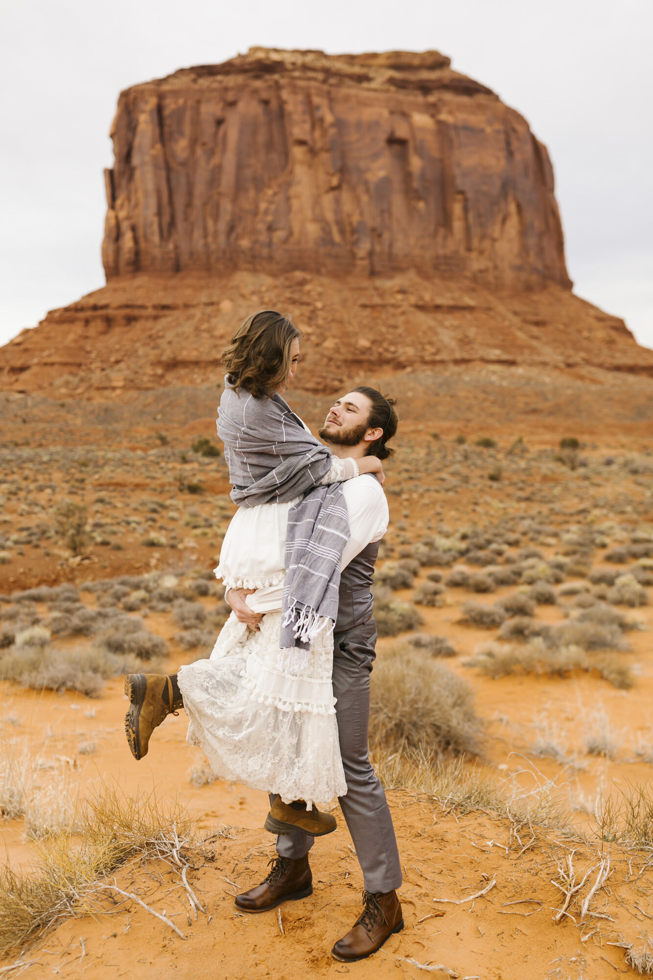 Groom picks up his bride to celebrate their wedding in Monument Valley Utah