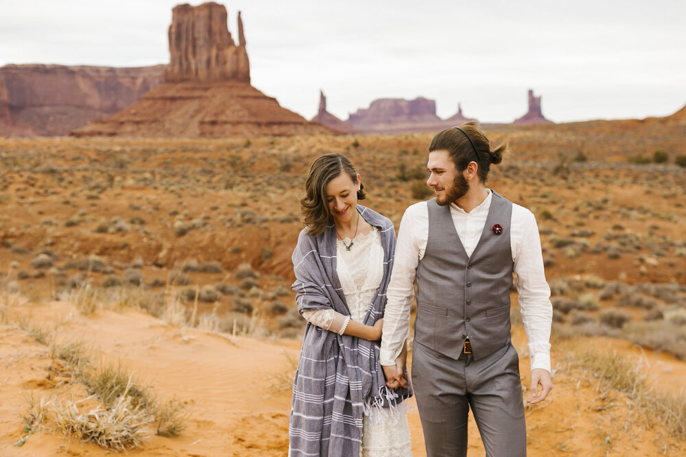 Just married couple walk together through Monument Valley on their wedding day