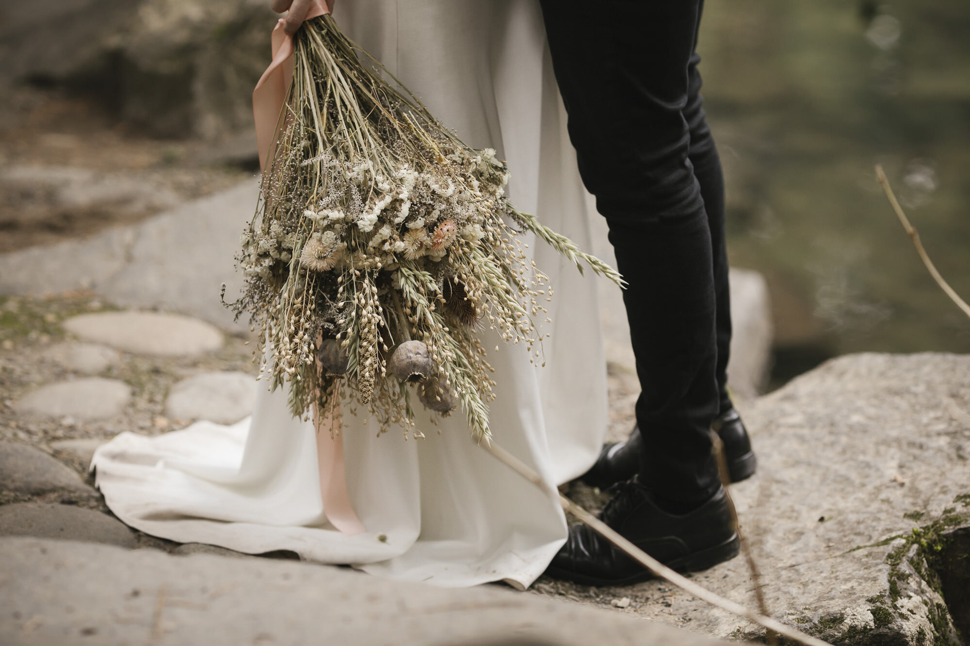Bride's bouquet of dried flowers with her partner on their wedding day