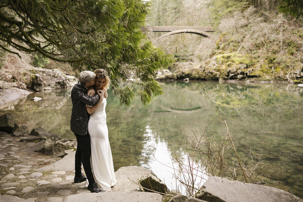 Wedding couple snuggle alongside the Lewis River in Washington