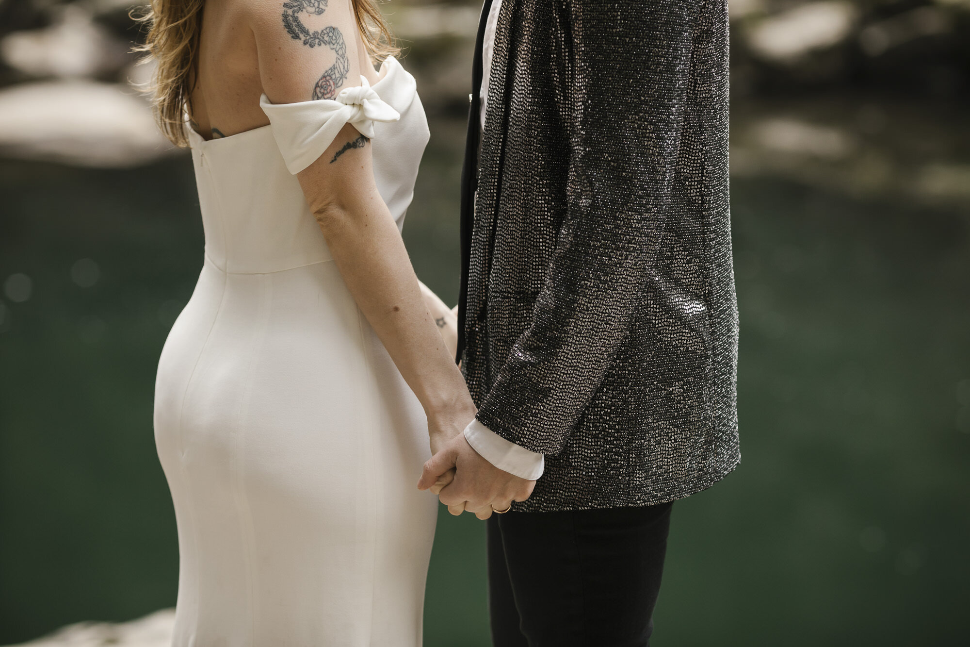 Bride with tattoos and strapless dress holds hands with her partner on their wedding day in Washington