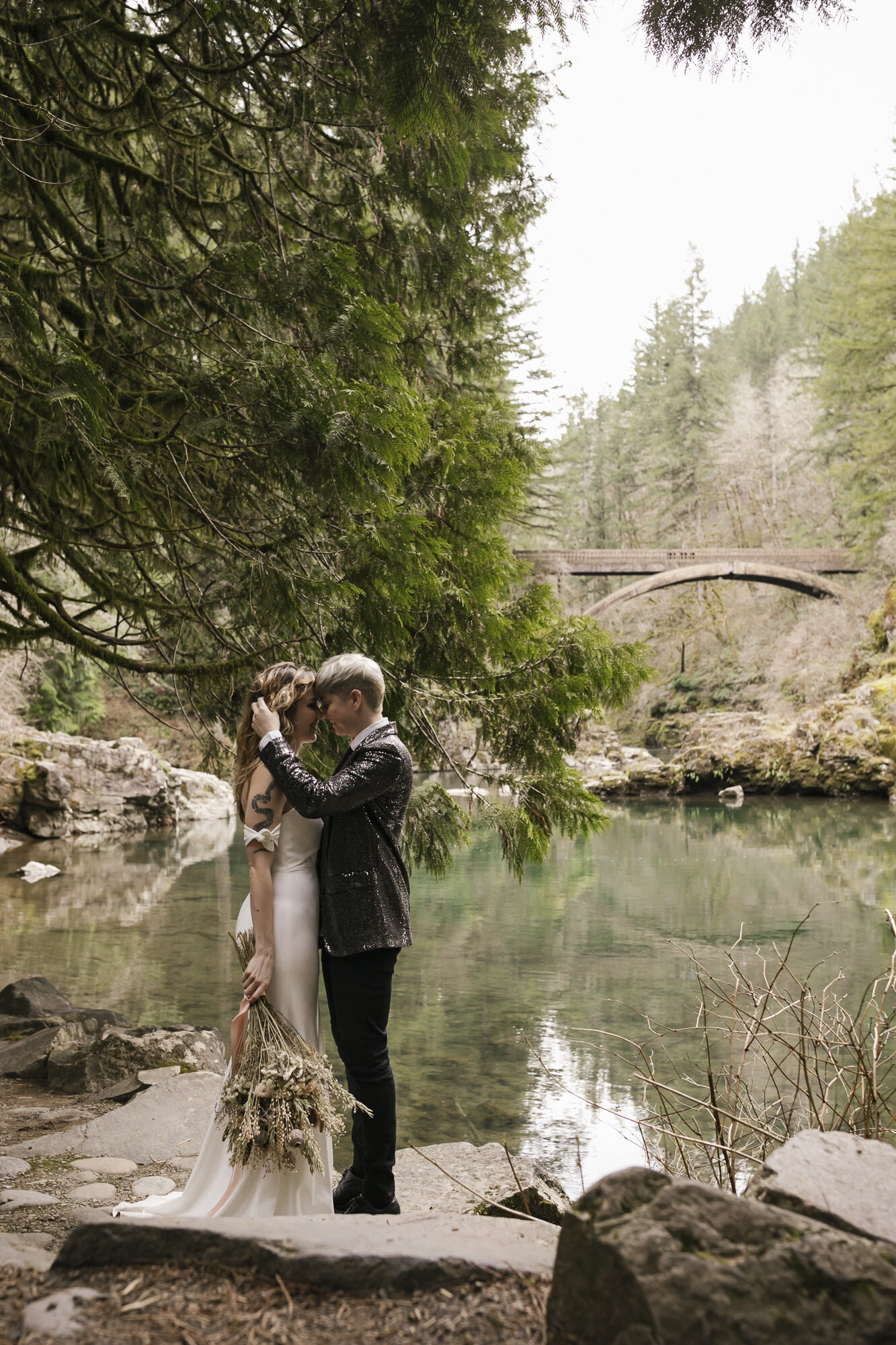 Same sex couple elope in a Washington forest along a river