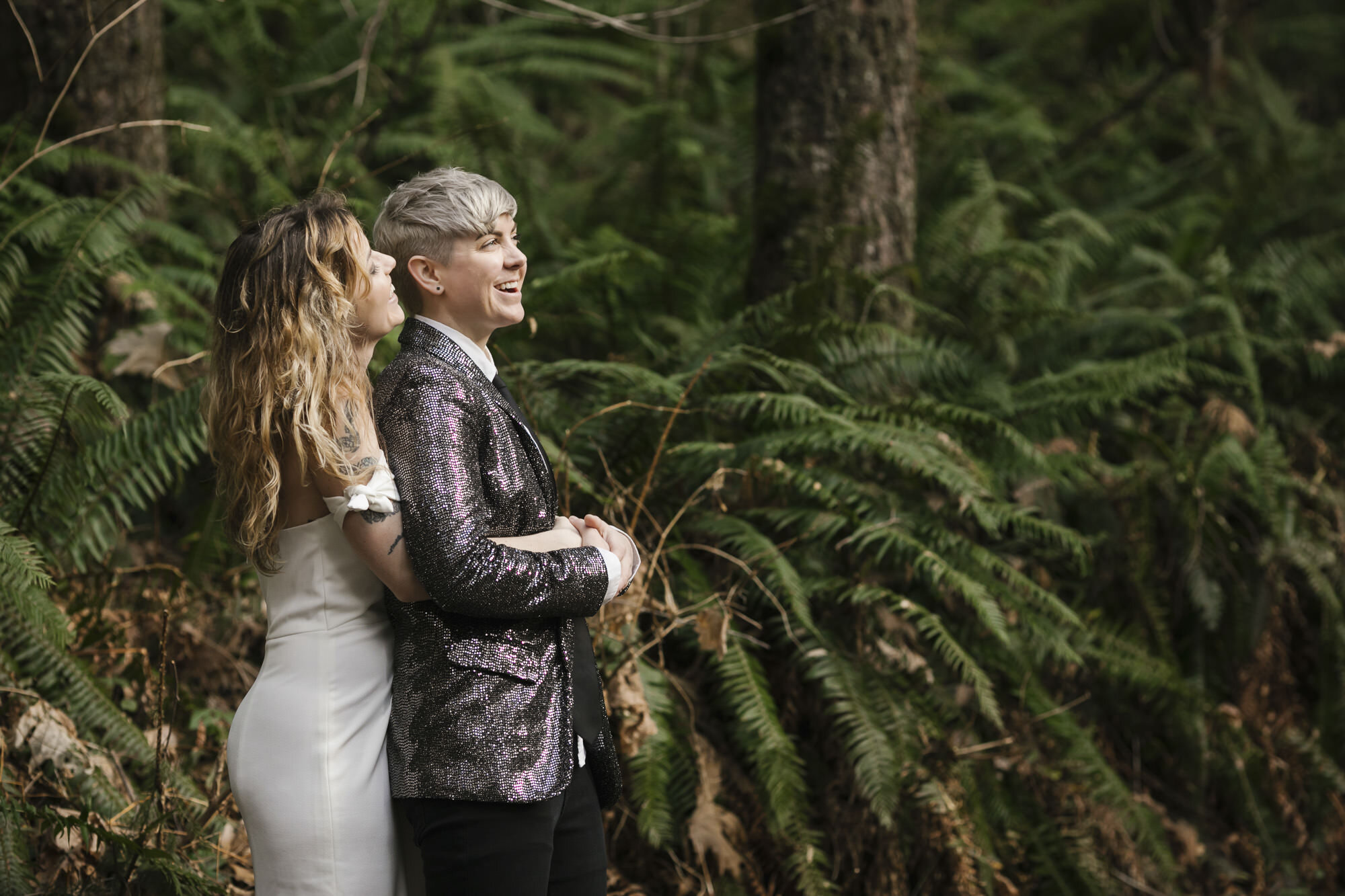 Wedding couple cuddle amongst the ferns in a forest in Washington