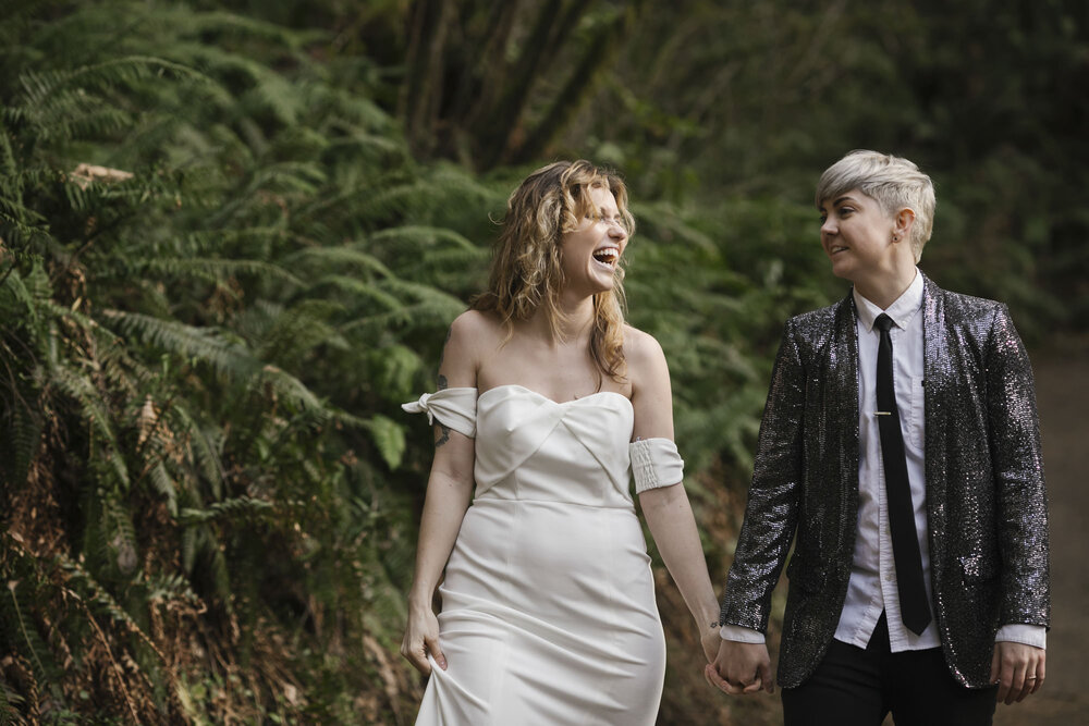 PNW couple laugh together as they walk through a forest in Washington during their elopement
