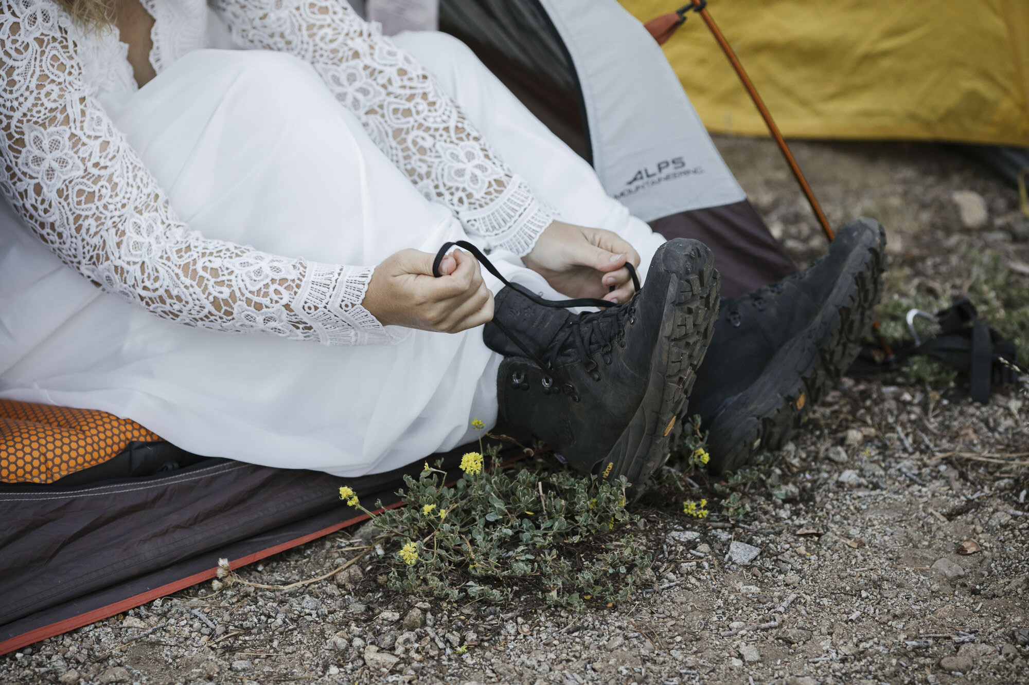 Bride putting on her hiking boots outside her tent during a backpacking mountain elopement