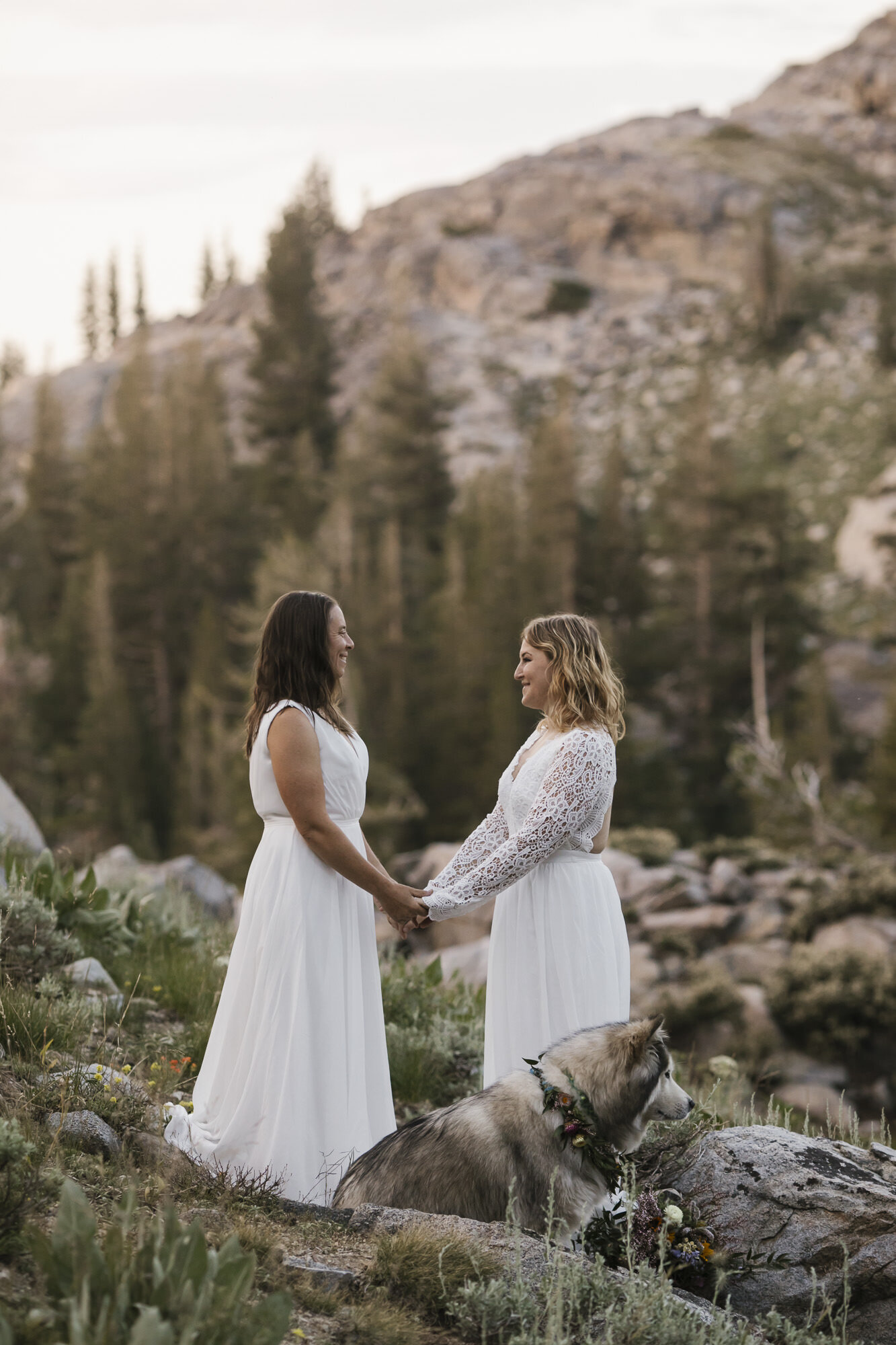 Lesbian wedding couple hold hands while exchanging vows during their mountain elopement
