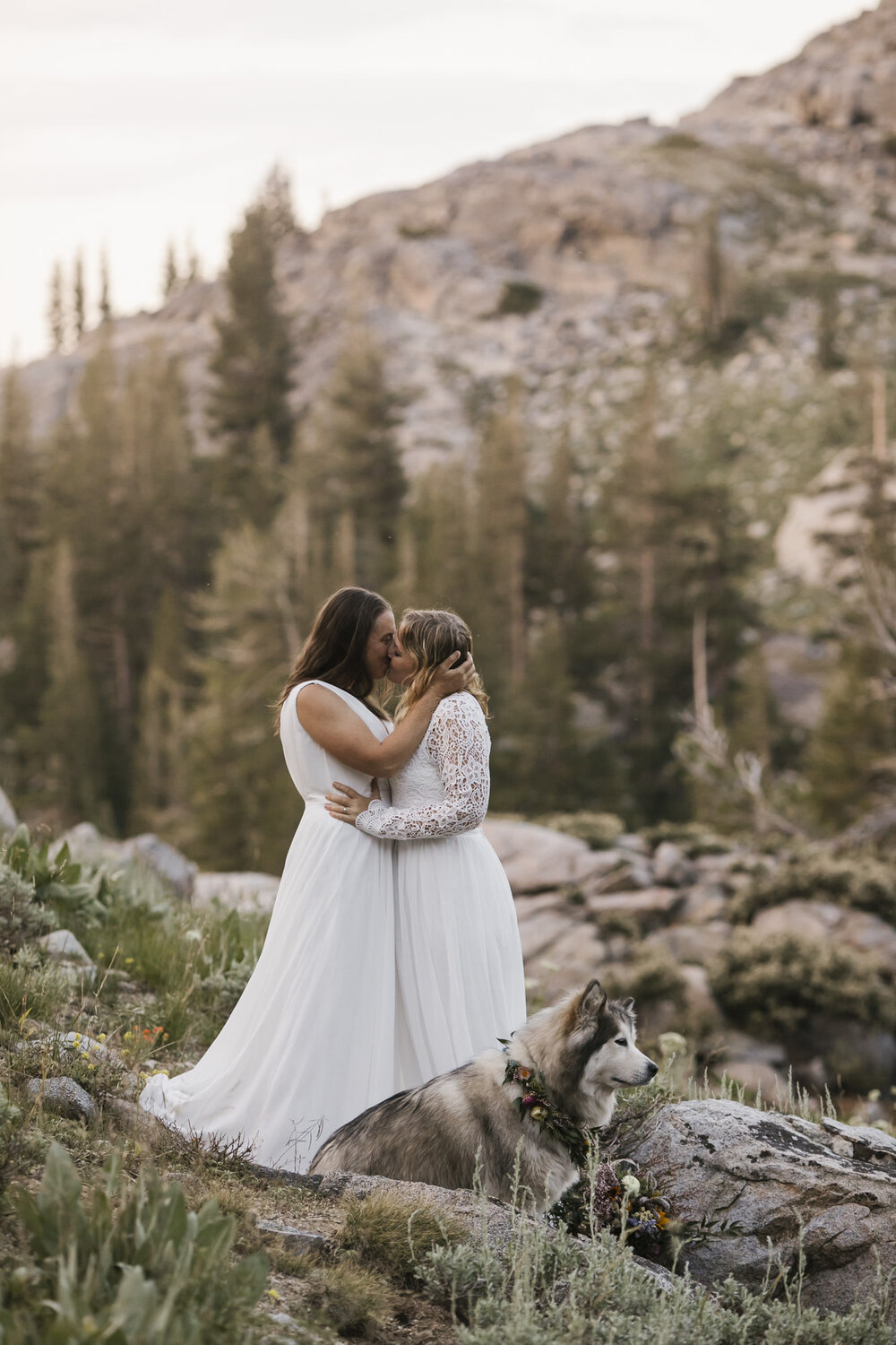 Two brides kiss after their wedding ceremony in the mountains