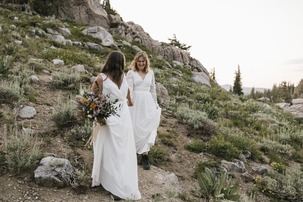 Two brides walk hand in hand during their hiking elopement