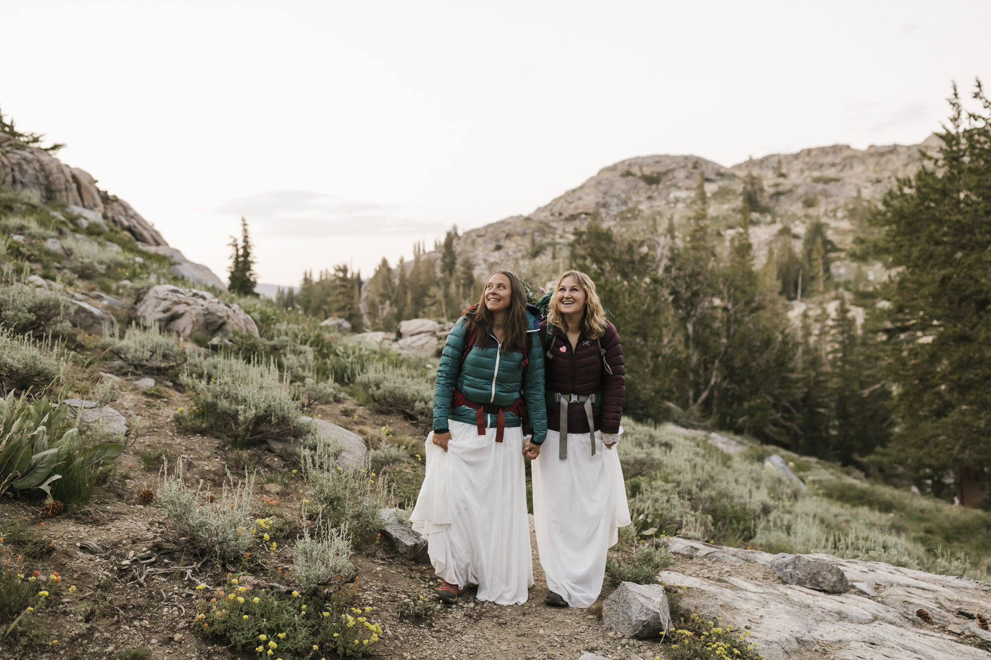 Adventurous wedding couple hike together and admire the sunset during their backpacking elopement in the California mountains