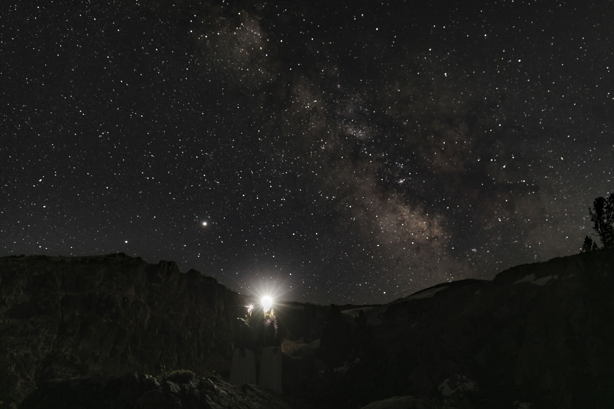 Wedding couple admire the Milky Way while shining their headlamps into the night sky