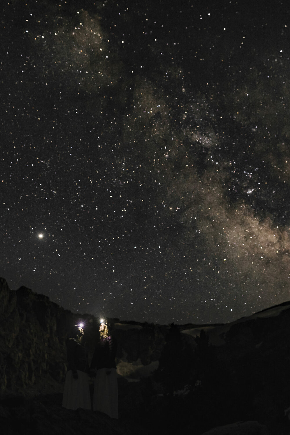 Wedding couple stand under the Milky Way while wearing their headlamps during their adventurous elopement
