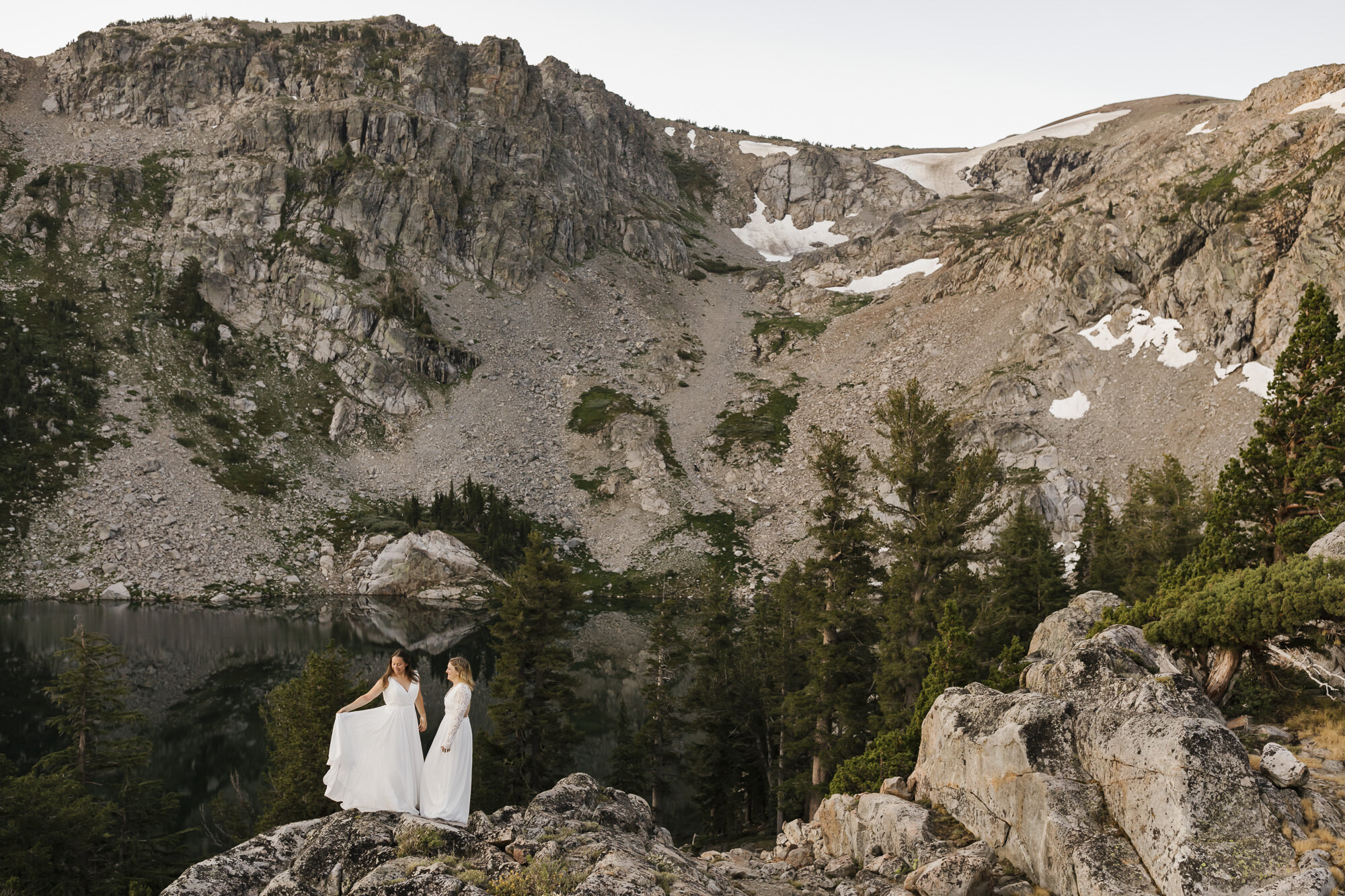 Wedding couple stand in front of alpine lake during their mountain elopement