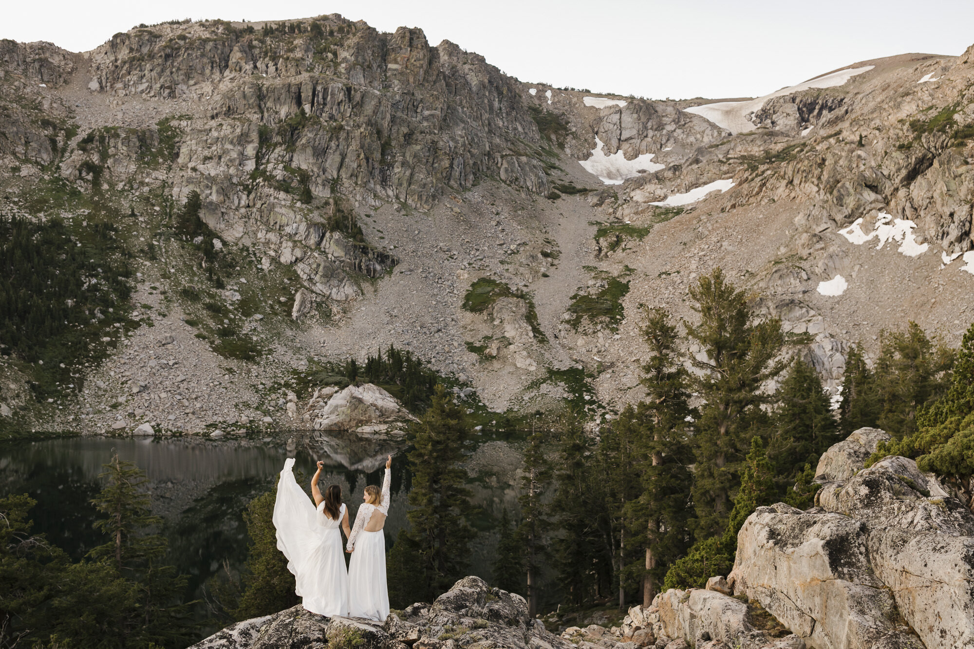 Two brides celebrate their marriage in the California mountains, wedding dress flying in the wind