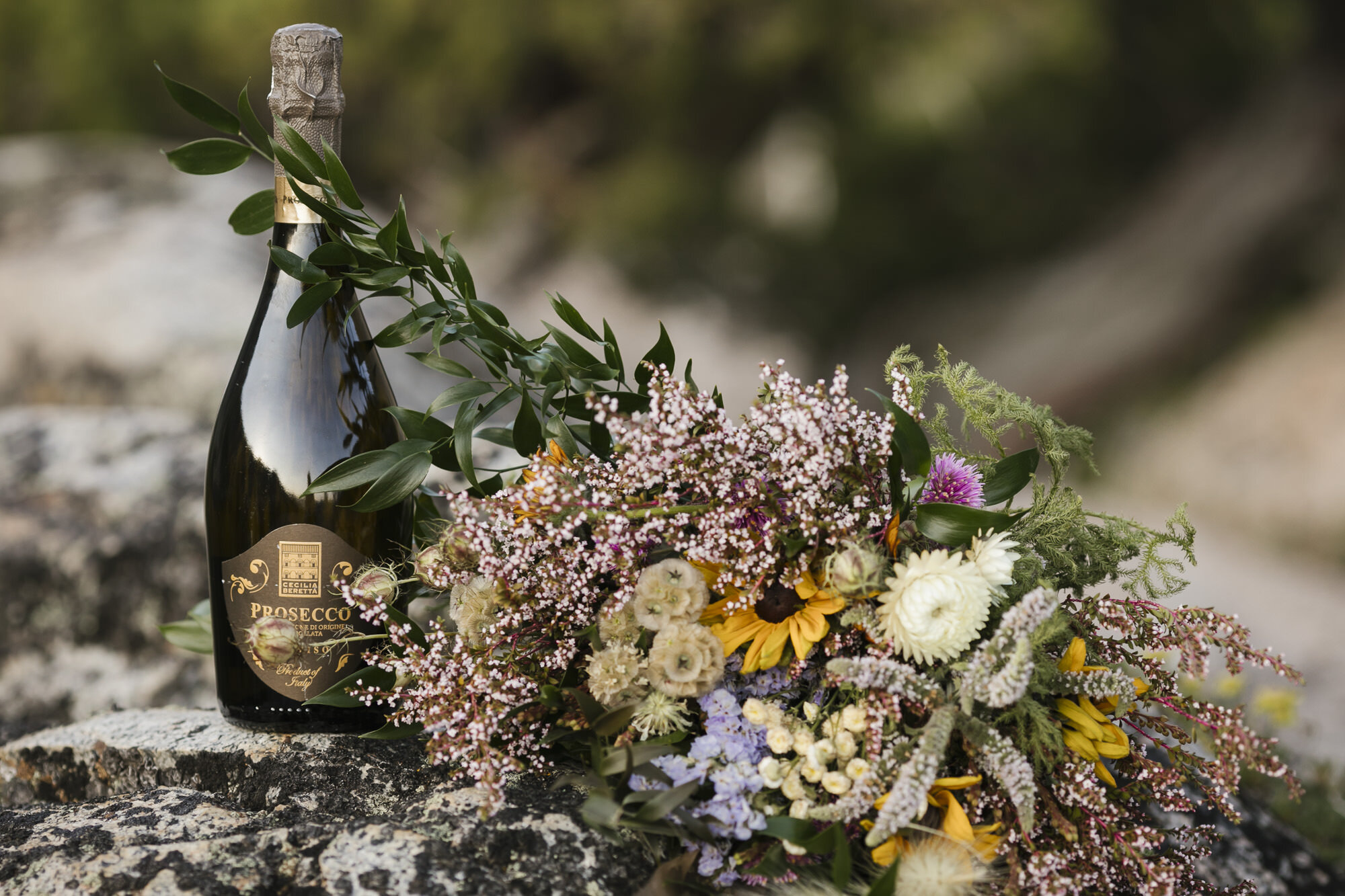 Bottle of prosecco next to bride's bouquet for backpacking elopement