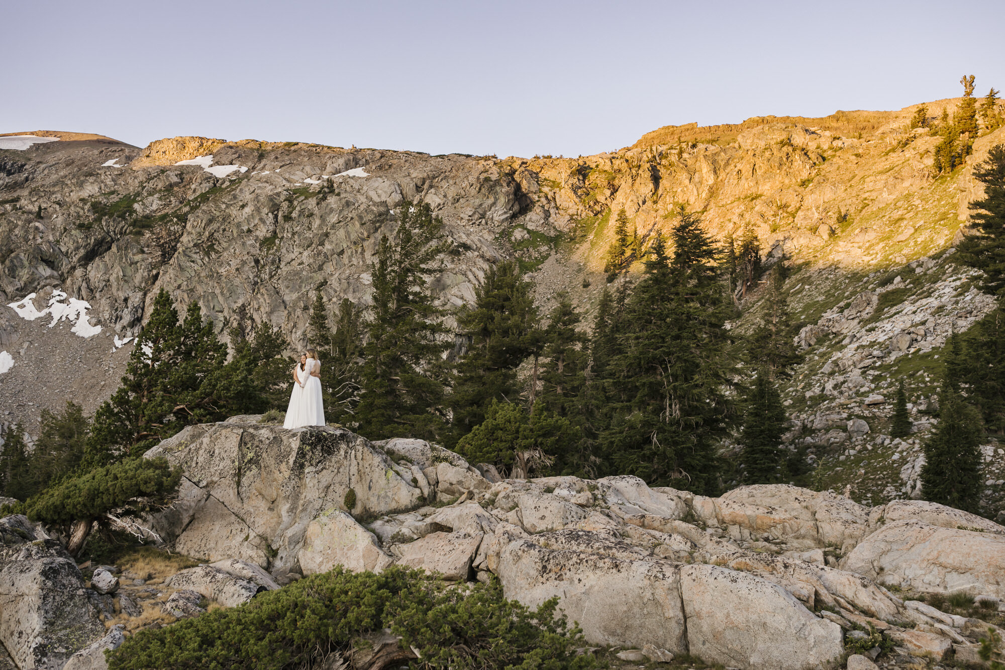 Just married couple stand together at sunrise in the California mountains
