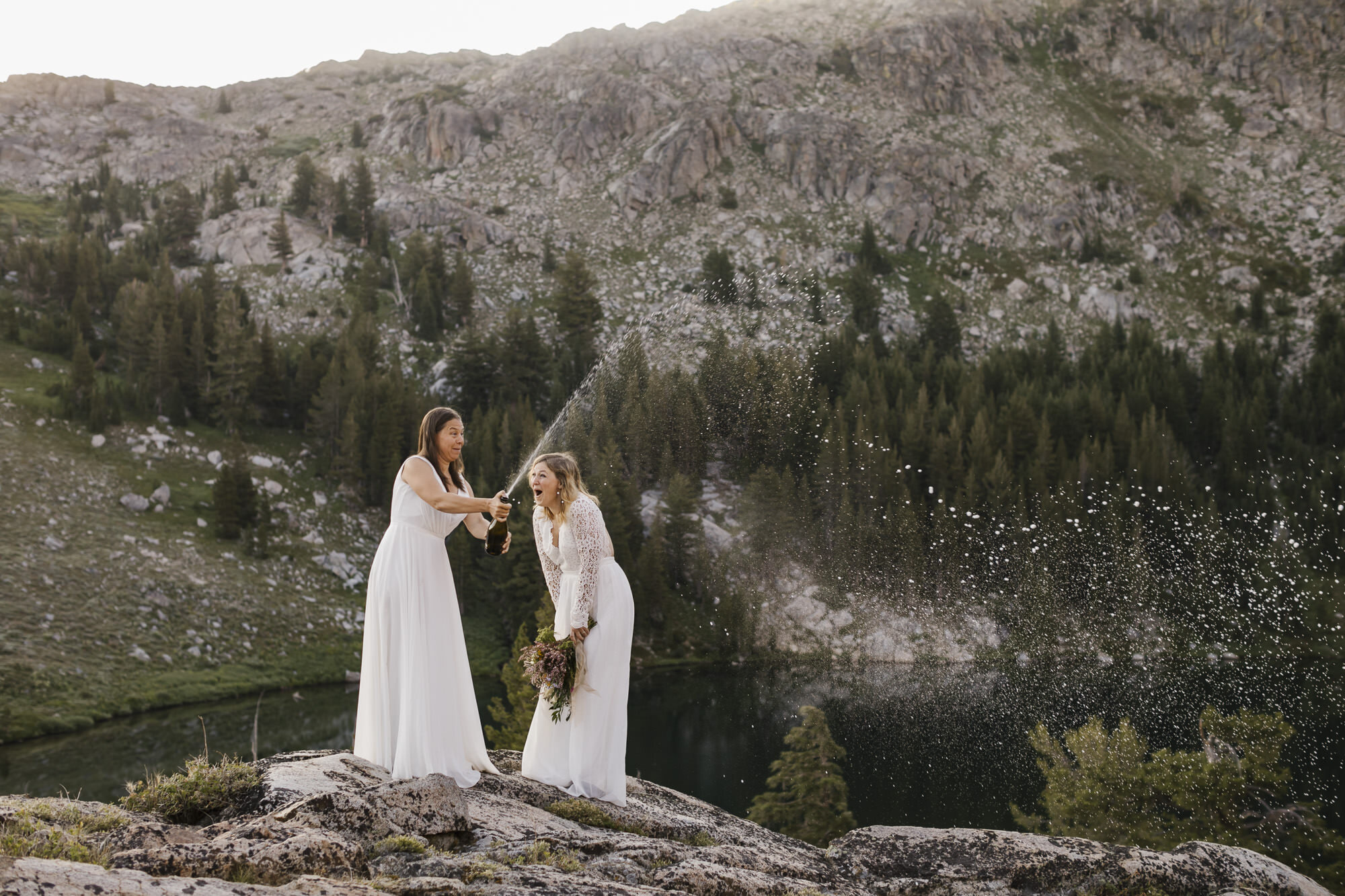 Brides pop champagne to celebrate their mountain elopement