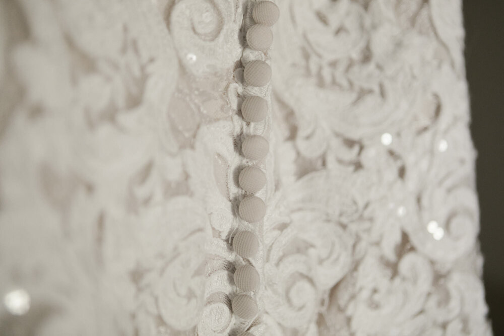 Detail shot of the back of the bride's wedding dress, lots of buttons and lace