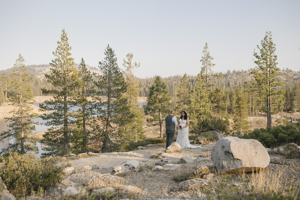 Wedding couple get married in the Tahoe forest in California with a lake behind them