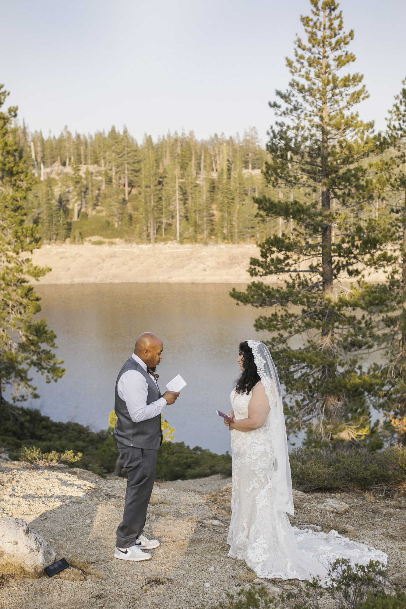 Wedding couple exchange vows in front of a lake in the Tahoe forest