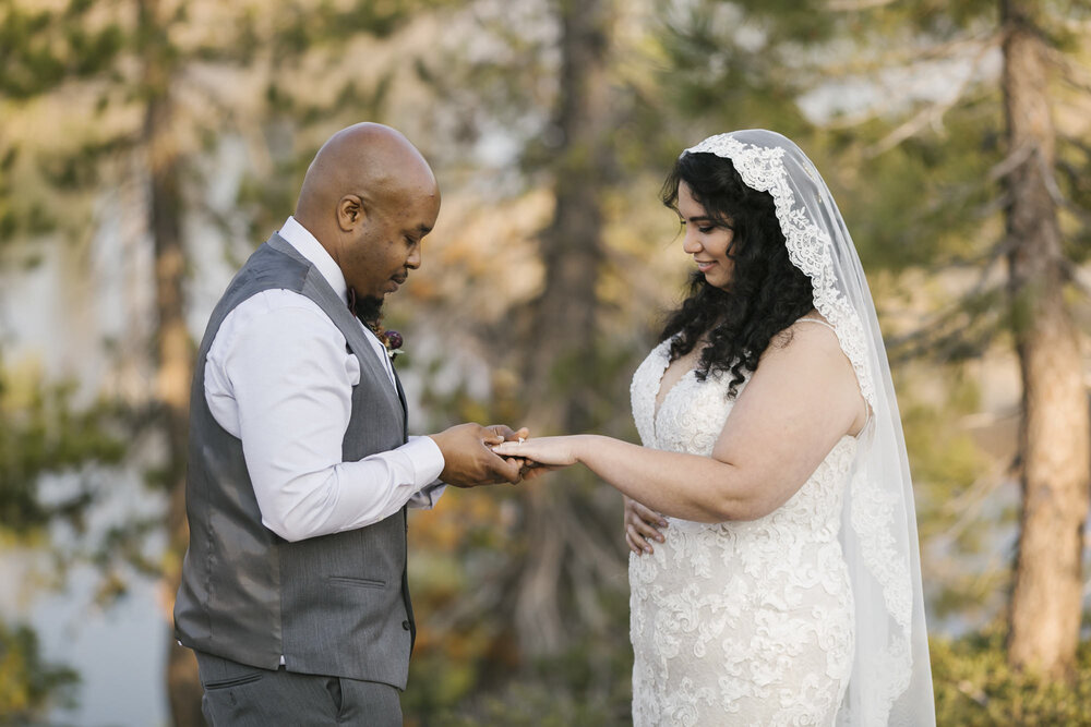 Groom places wedding band on his bride's ring finger