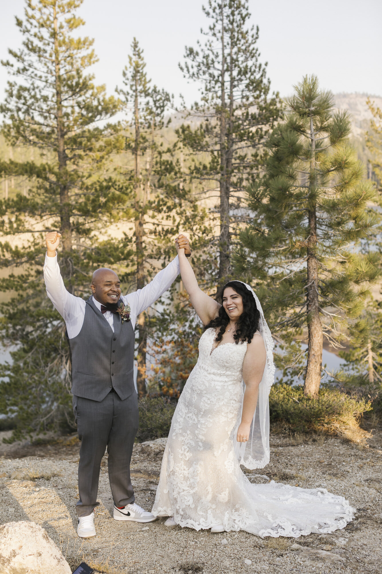 Bride and groom raise their arms in celebration after getting married in the Tahoe forest