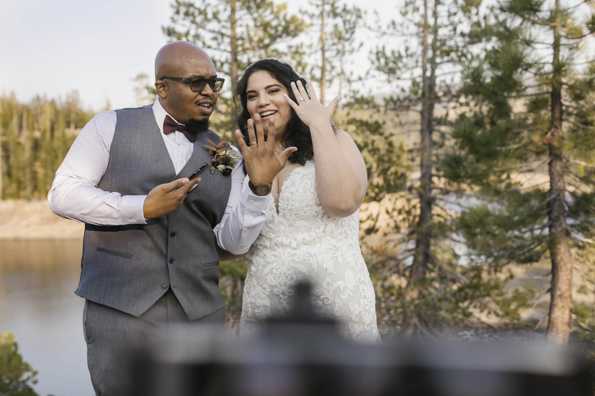 Wedding couple show off their wedding rings to their families who are watching over Zoom
