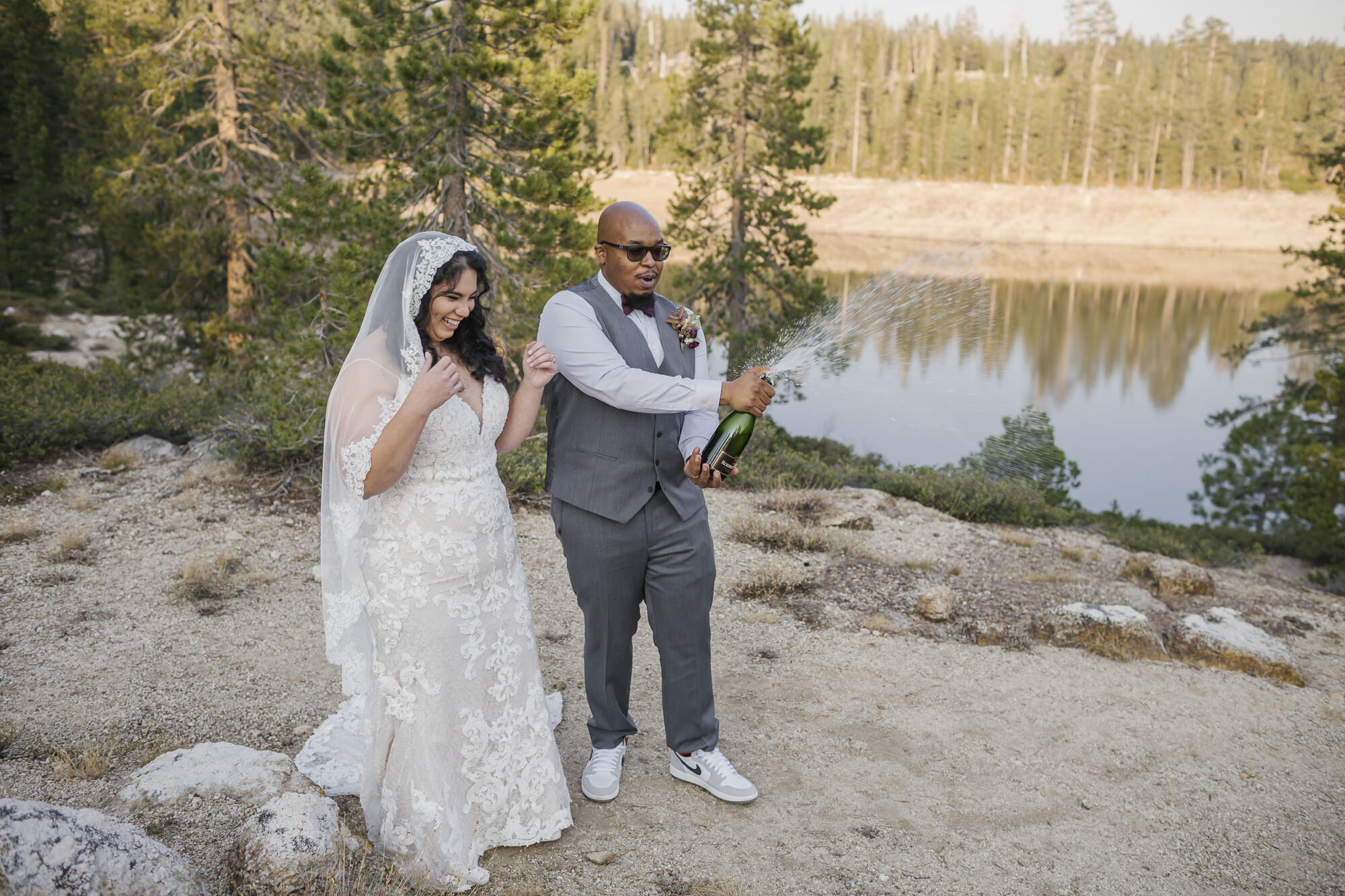 Wedding couple pop champagne in the Tahoe forest to celebrate their elopement