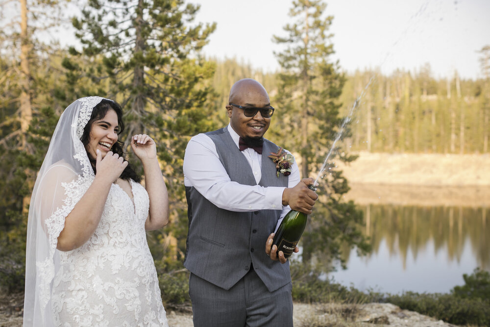 Wedding couple pop champagne in the Tahoe forest to celebrate their elopement