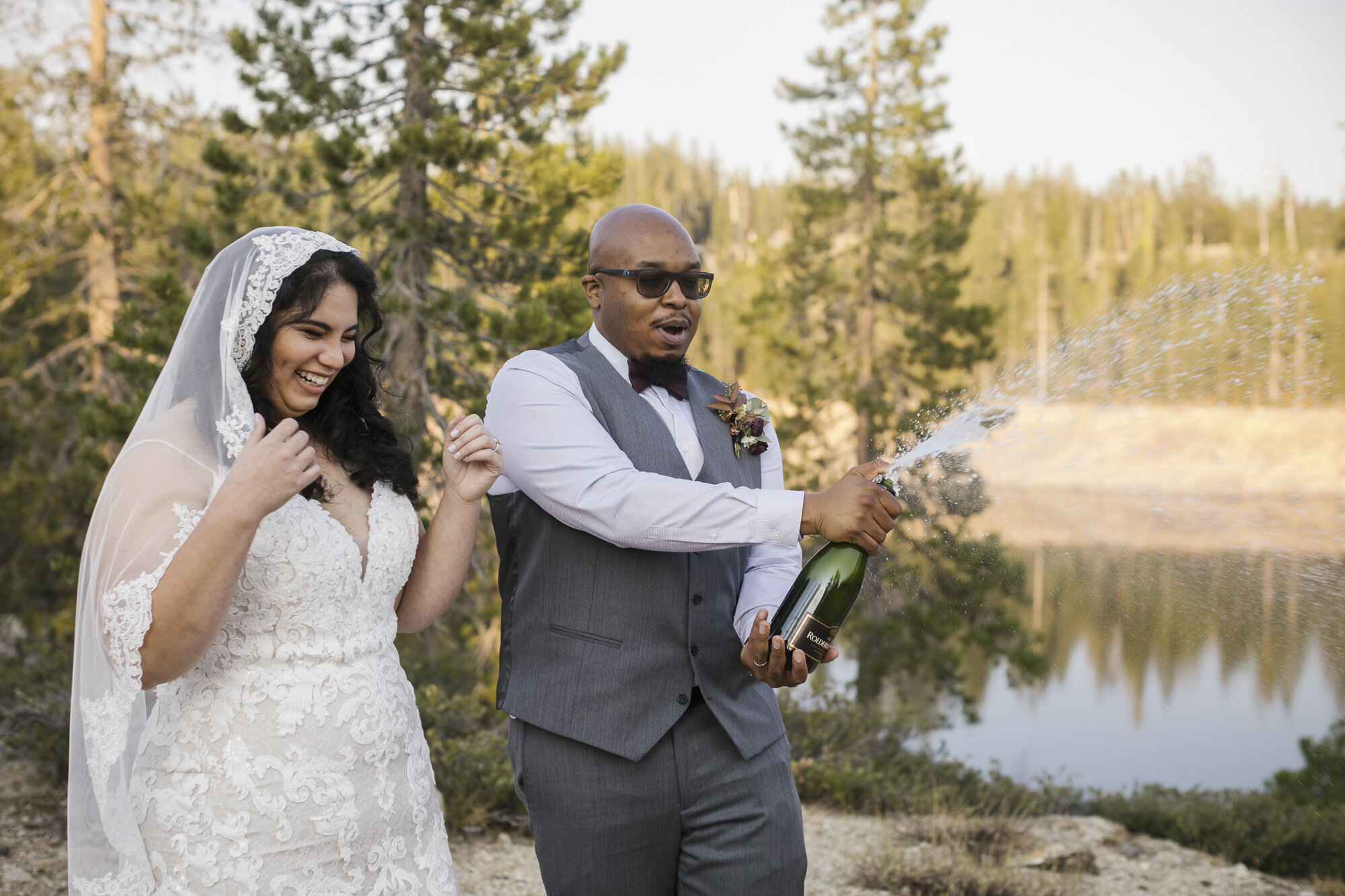 Wedding couple pop champagne in the Tahoe forest to celebrate their elopement