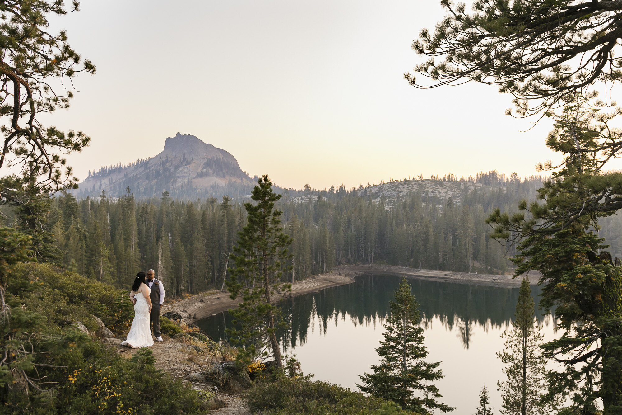 Wedding couple overlook lake and mountain in Tahoe forest during their adventurous elopement