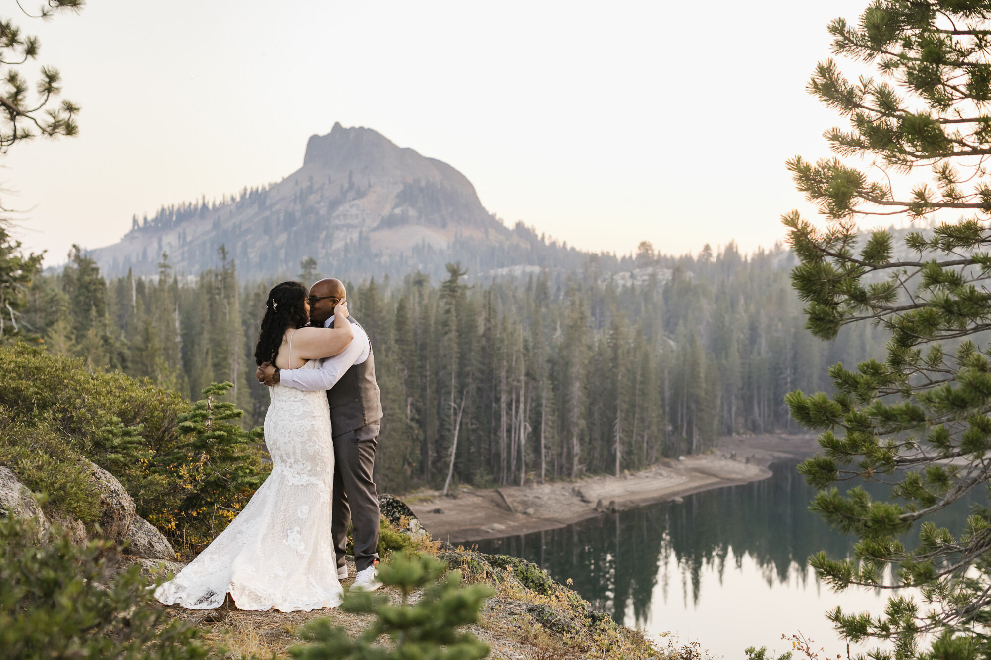 Wedding couple kiss in front of mountain peak in Tahoe forest