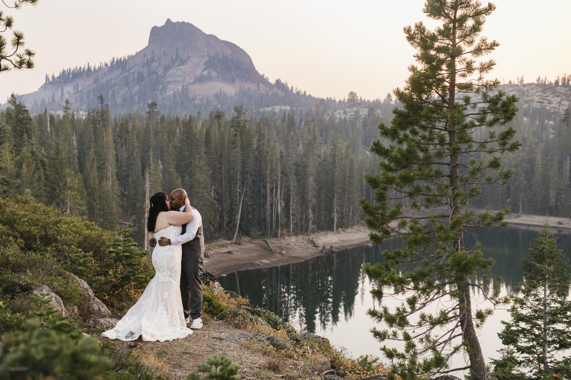 Just married couple kiss in front of mountain peak in Tahoe forest during their adventurous elopement