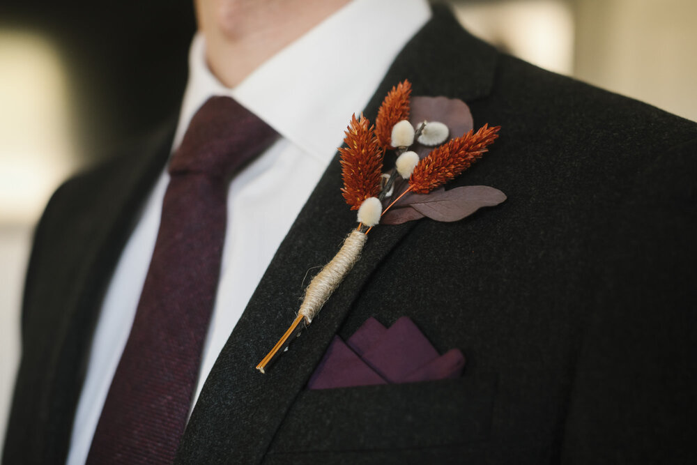 Detail shot of the groom's boutonniere, purple tie, and purple kerchief 