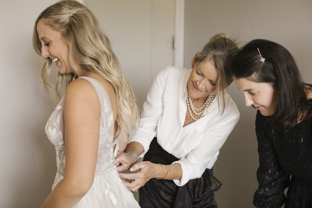 Mom and sister help the bride into her BHLDN wedding dress