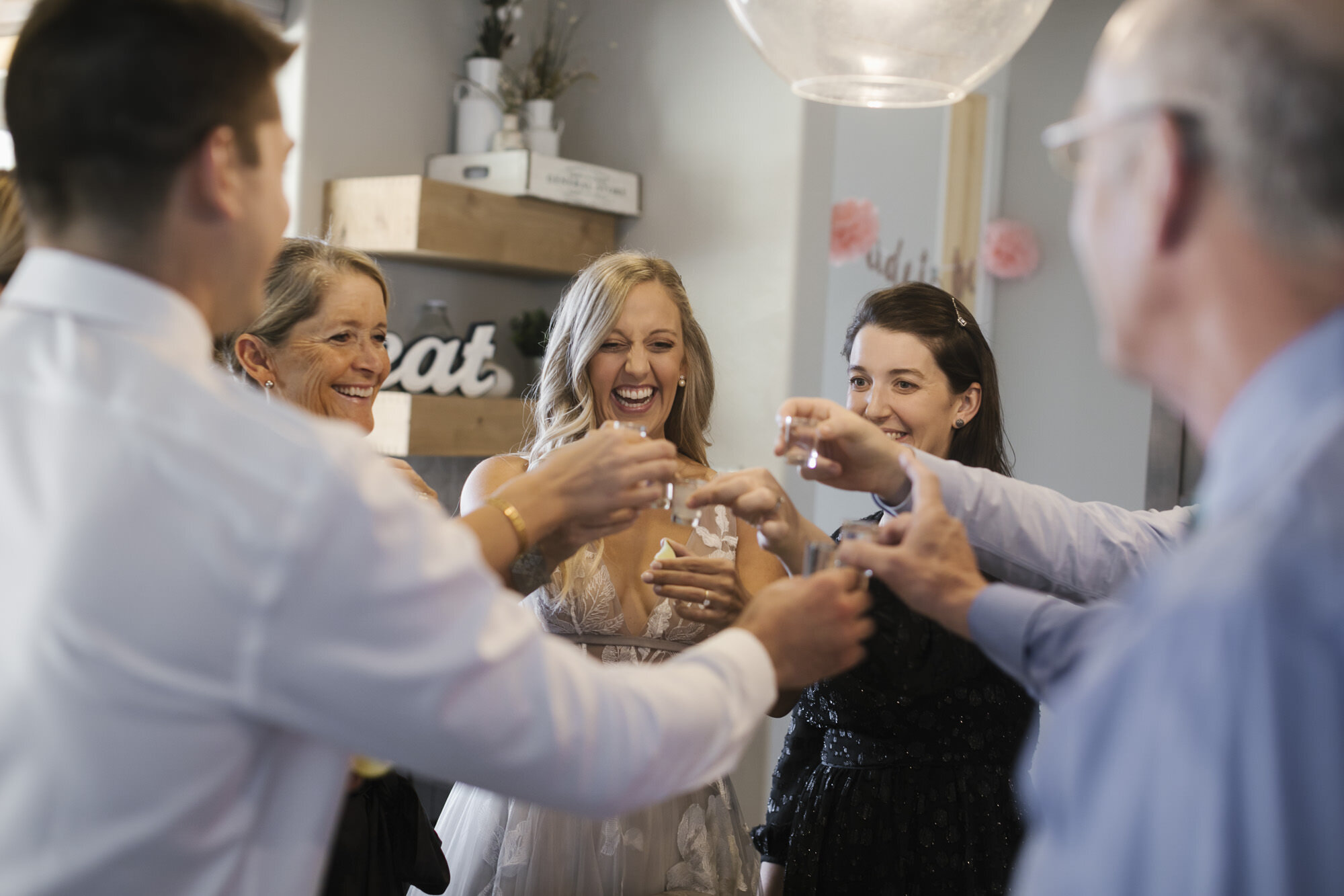 Bride and family take a wedding day tequila shot together as a group
