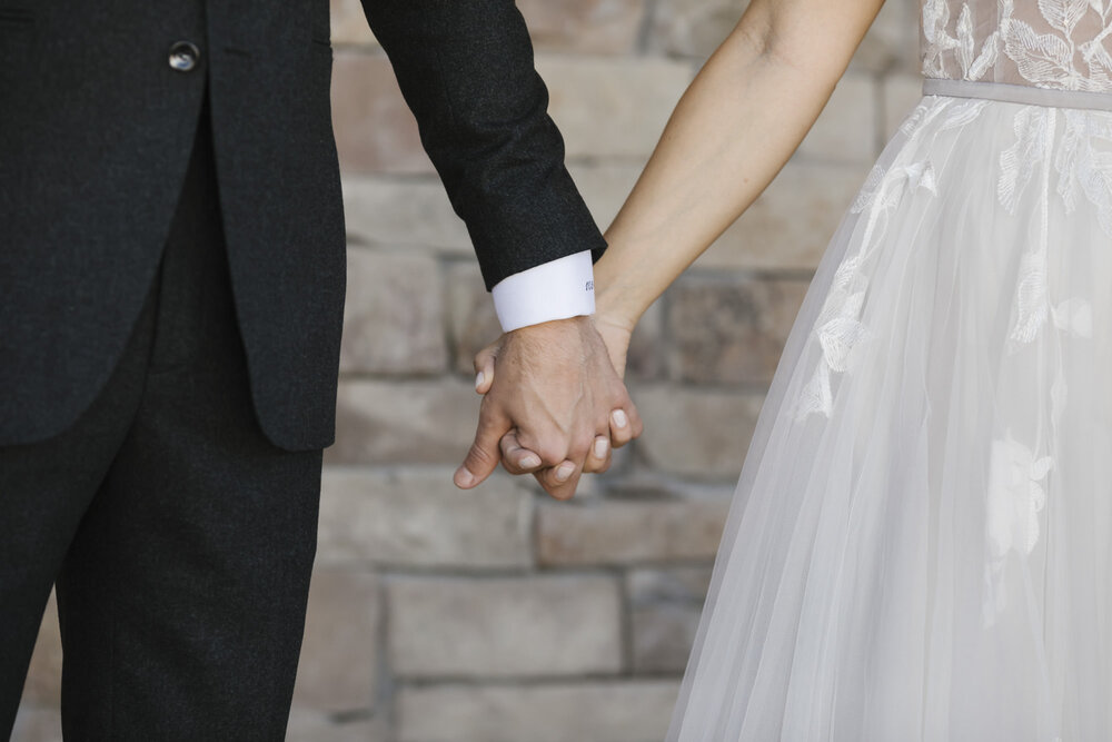 Detail of bride and groom holding hands