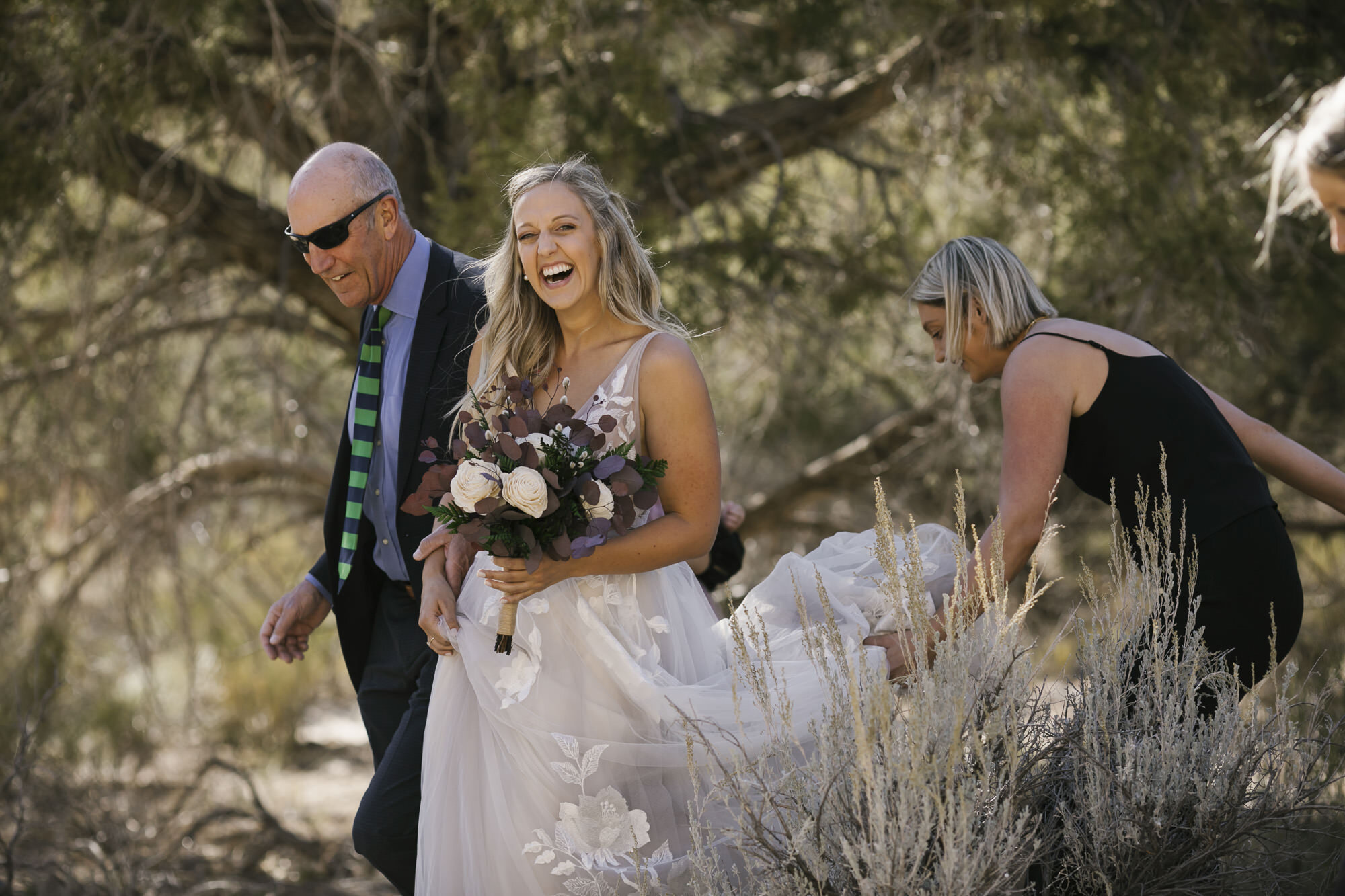 Brides joyfully walks into her Utah desert wedding ceremony with the help of her parents and sister