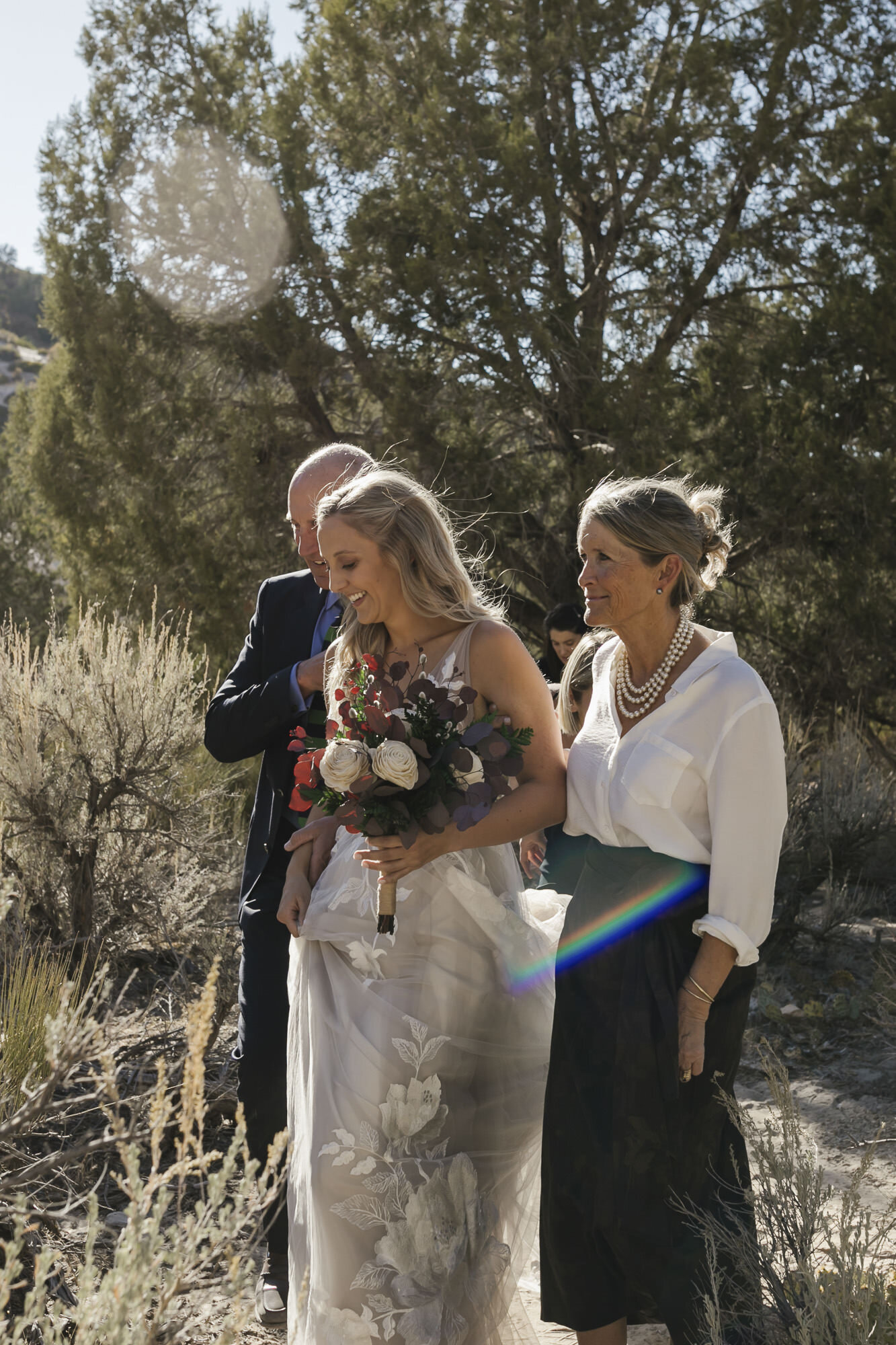 Utah bride walks with her parents into her desert wedding ceremony