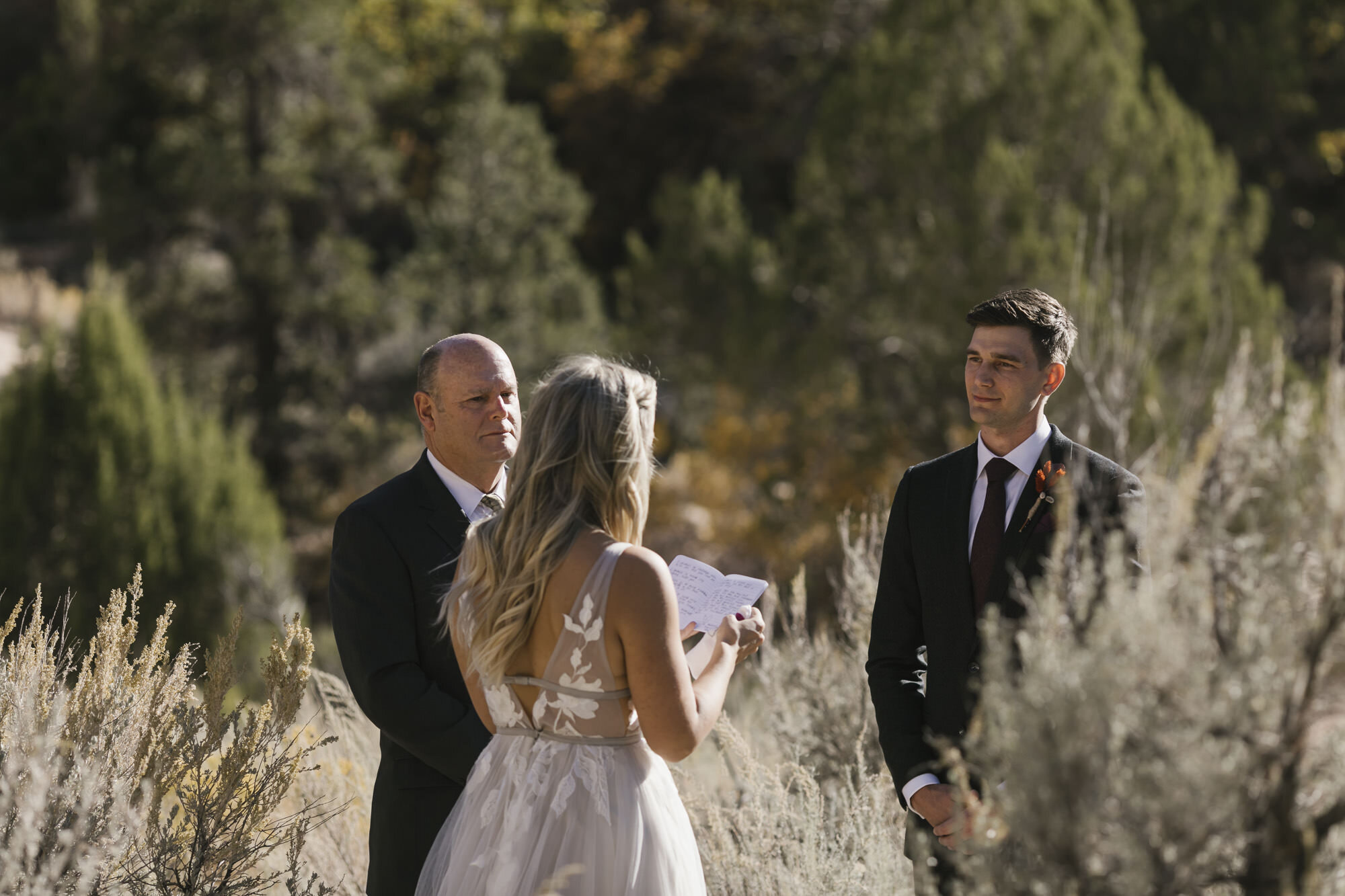Utah groom listens to his bride reading her wedding vows in the desert in Utah