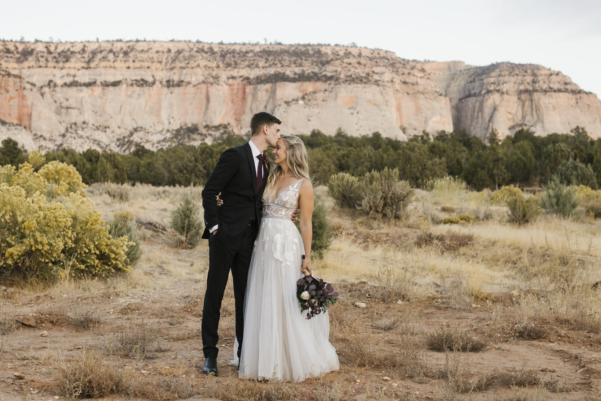 Groom kisses his bride's forehead just outside of Zion during their Utah desert wedding